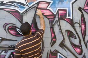 man vandalizing wall with graffiti